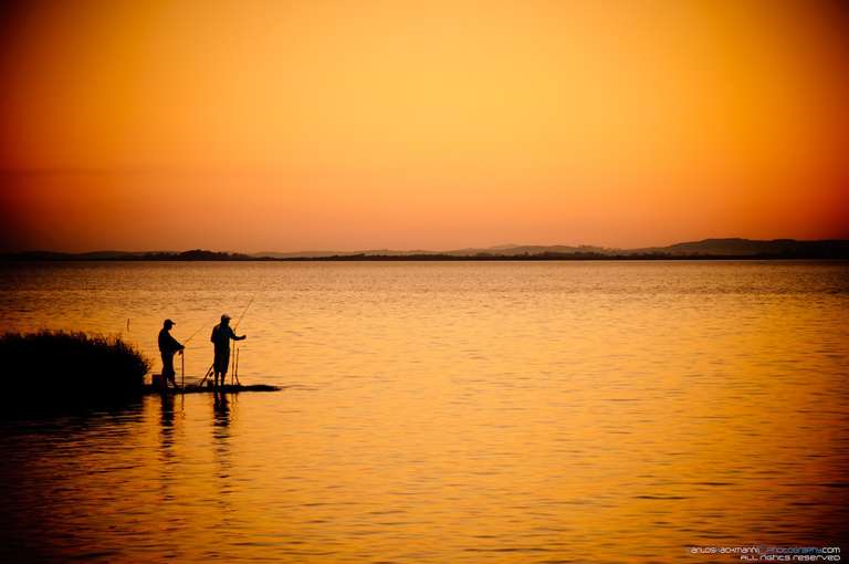 beautiful lake landscape with two man silhouette fishing during sunset