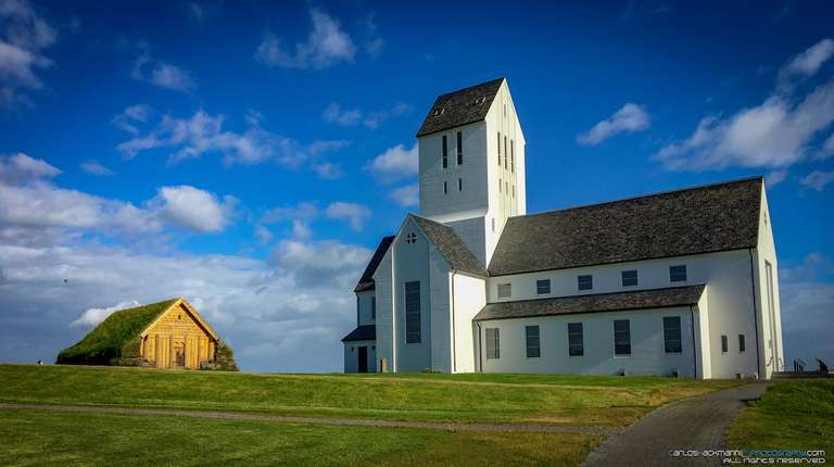 icelandic Cathedral near a turf house in a green field