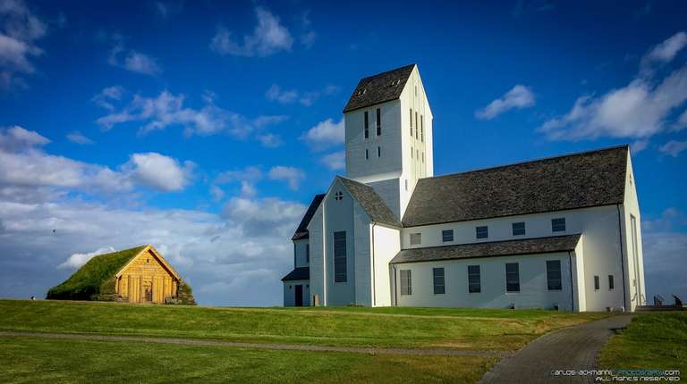 icelandic Cathedral near a turf house in a green field